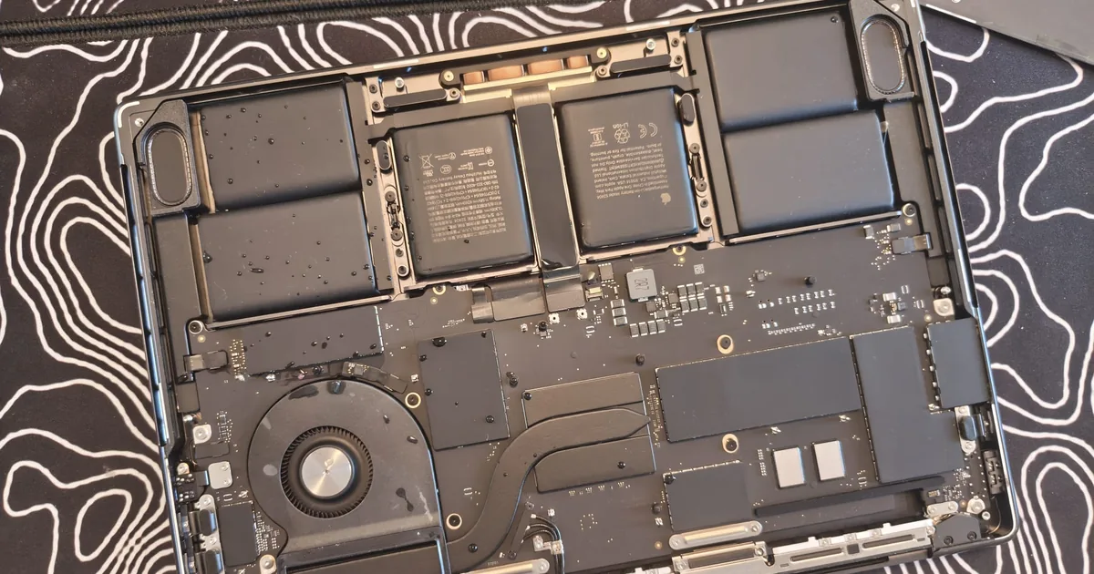MacBook Pro 14" M5 (A3434) deschis în service după apă vărsată: picături de apă pe baterie și pe placa de bază