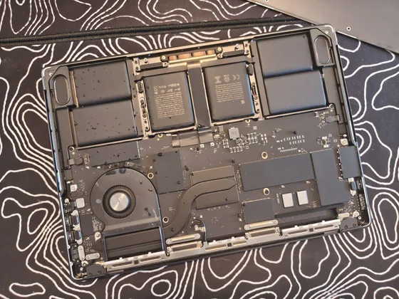 MacBook Pro M5 deschis în service: picături de apă pe baterie și pe placa de bază