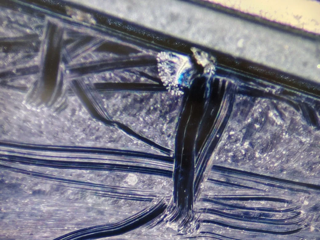 Punctul de pornire al fisurii pe un display de MacBook, mărit la microscop