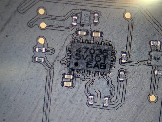 Aceeași zonă după curățarea oxidării — circuit integrat cu marcaj lizibil și pad-uri curate pe placa MacBook Pro M5