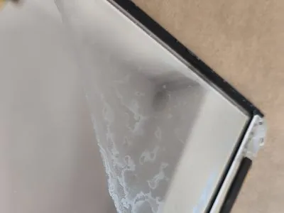Folii backlight display MacBook cu urme albe de lichid — pete caracteristice după contact cu apă sau cafea