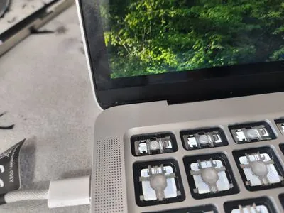 MacBook Pro cu taste lipsa pe tastatura, cleme rupte si mecanisme scissor expuse - rezultat tipic dupa socuri mecanice sau presiune pe carcasa